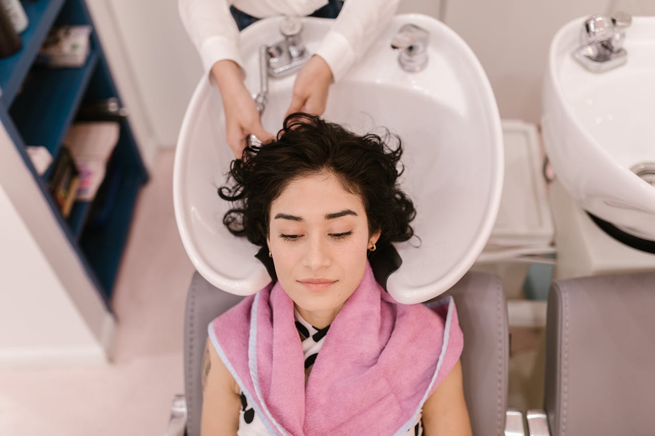 A woman enjoys a relaxing hair wash at a modern hair salon, focusing on self-care.